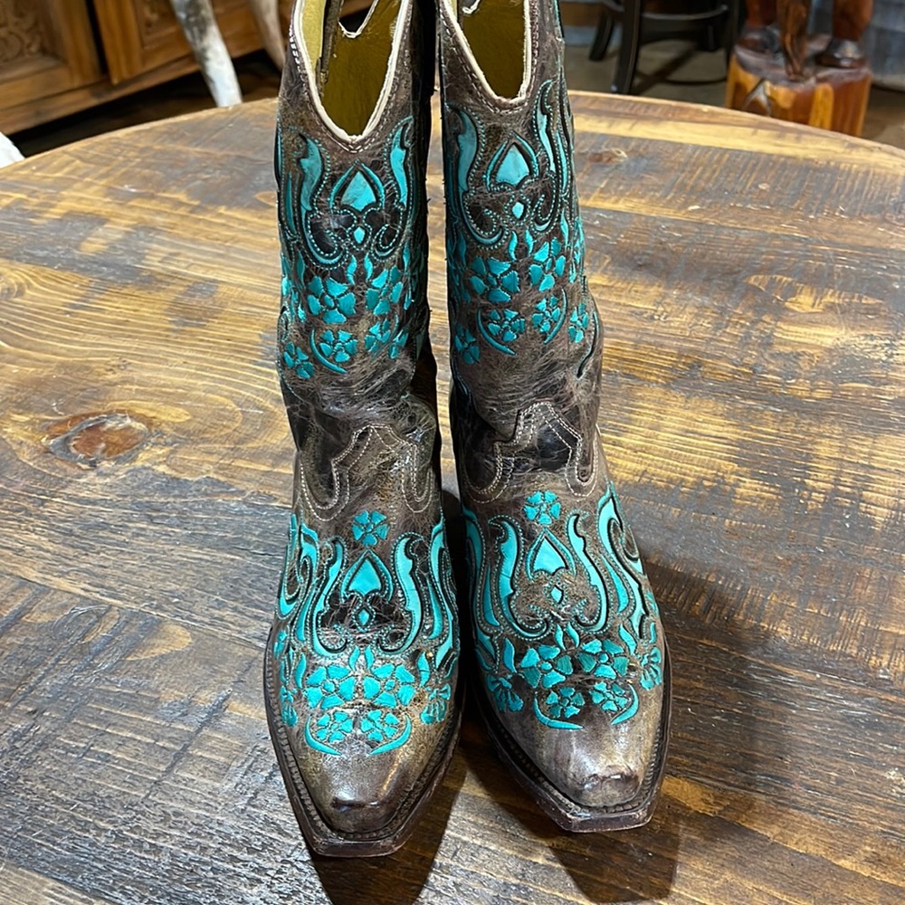Turquoise and brown lazer cut boots with embroidered floral designs .